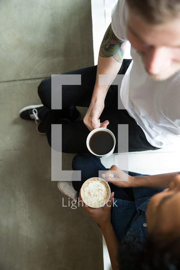 A man and woman sitting and having coffee together.