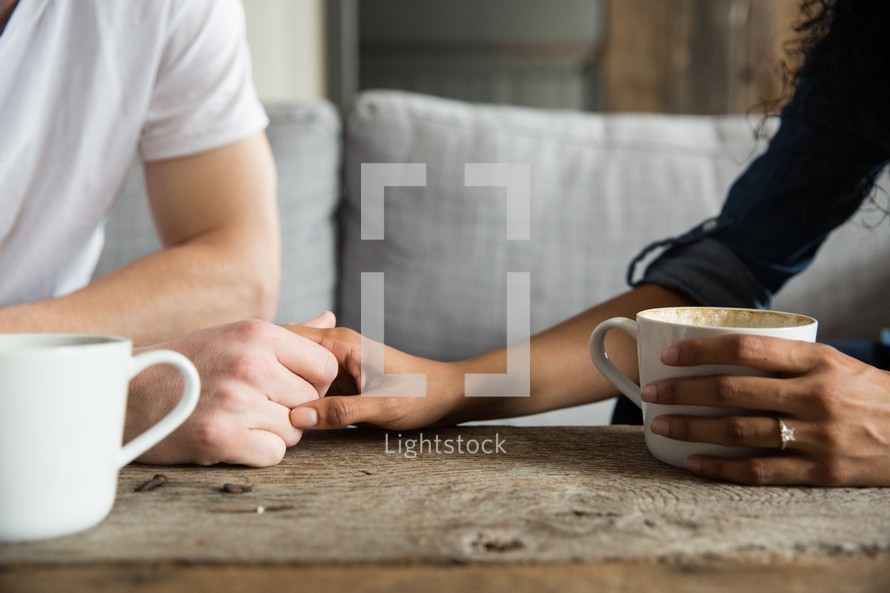 mugs of coffee and a couple holding hands 