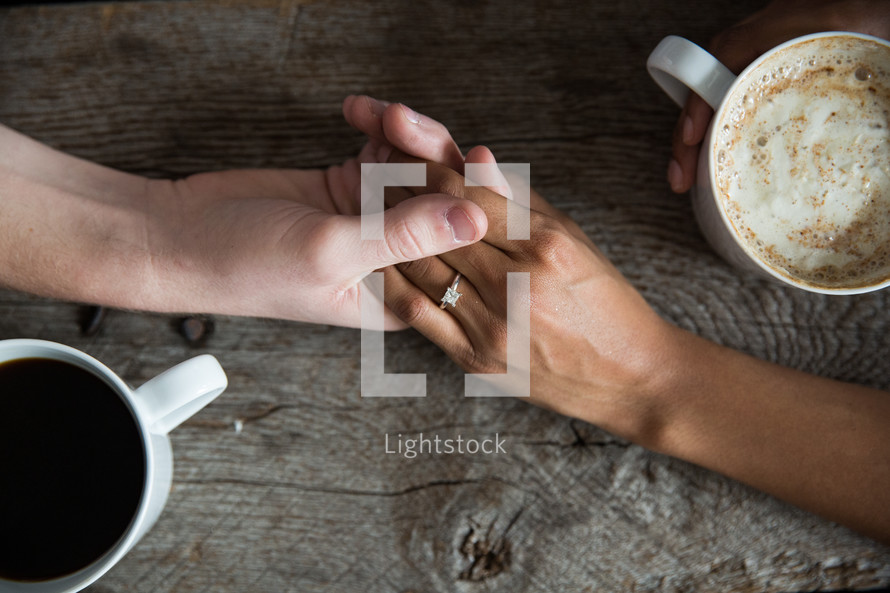 a couple holding hands and mugs of hot cocoa 