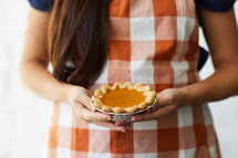 a woman holding an individual size pie 