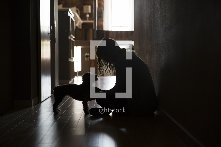 a woman sitting in dark hallway with her dog 
