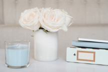roses in a vase, candle, and journals