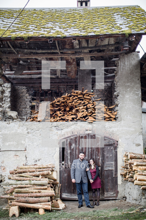 a couple standing in front of an old wood mill 