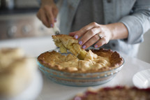 a woman cutting a slice of apple pie