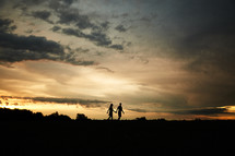 silhouette of a couple walking holding hands at sunset 