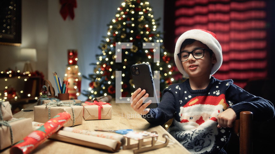Little Boy using his Smartphone to show his Christmas tree 
