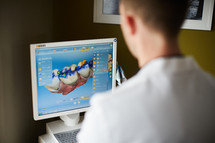 dentist looking at computer scans of teeth 