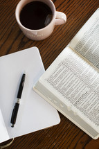 journal, pen, open Bible, and coffee mug on a table 