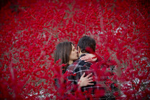 a couple kissing between branches covered with red berries