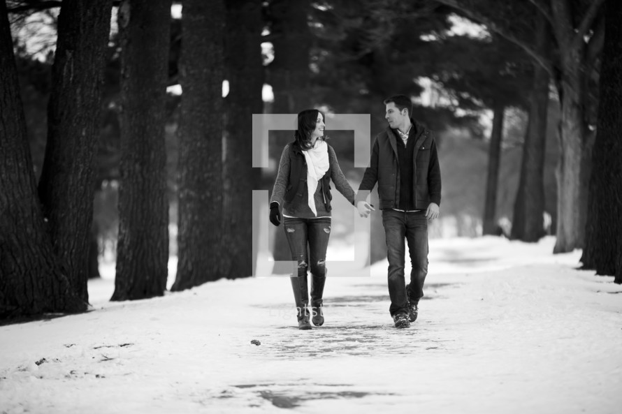 man and woman walking holding in the snow 