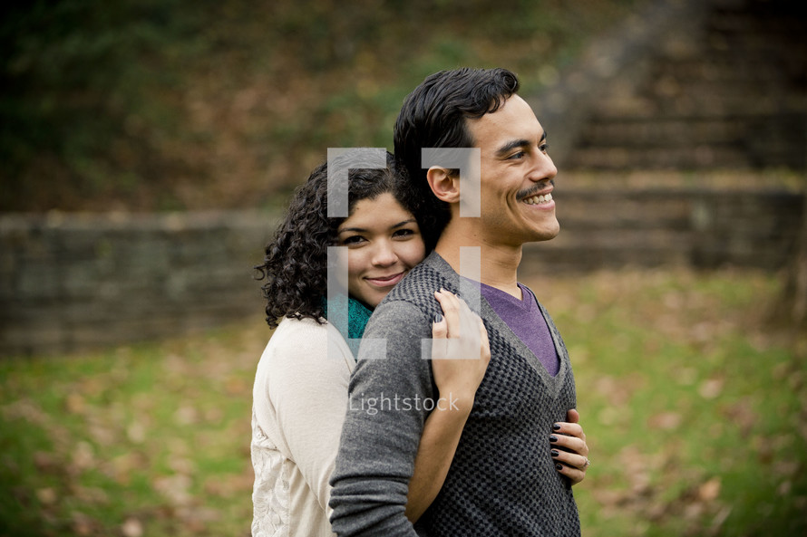 Woman embracing man from behind in park.
