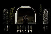 a couple kissing under an archway at night