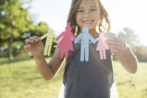 a girl child holding paper dolls 
