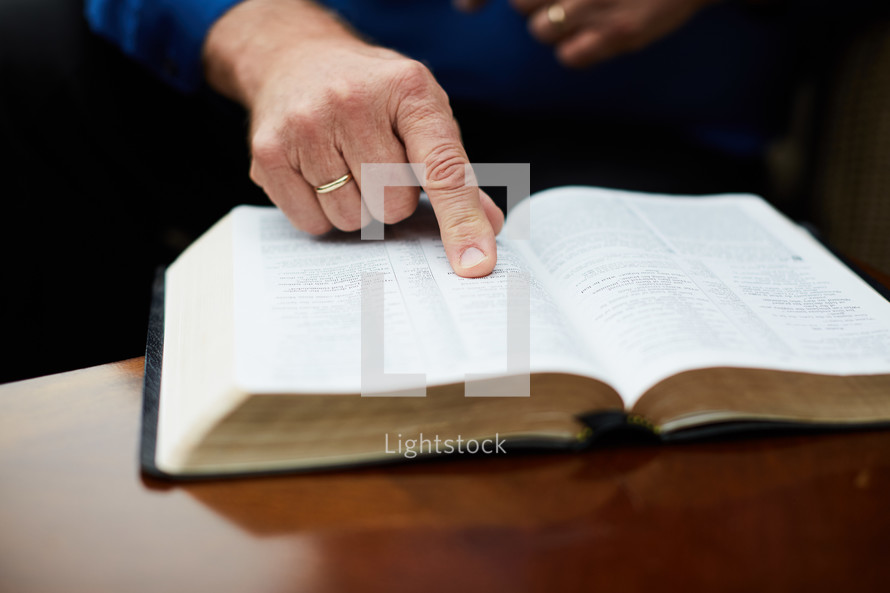 elderly man with his finger pointing to scripture 