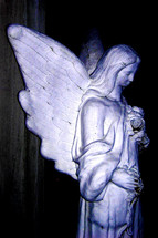 A pensive statue of an Angel with outspread wings guarding over a dearly departed loved one. 