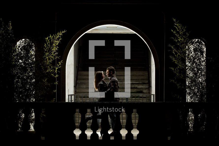 Couple embracing in lighted archway.