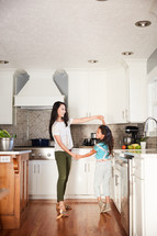 a mother and daughter dancing in a kitchen 
