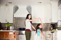 a mother and daughter dancing in a kitchen 