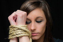 Woman with her wrists bound by rope.