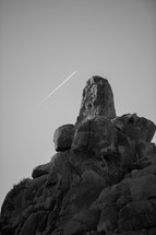 jet streak in the sky over a rock peak 