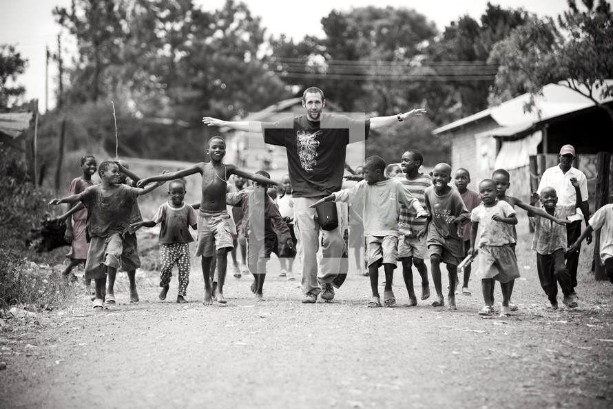 man followed by a group of children