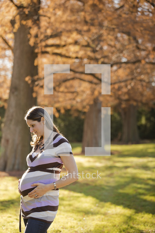 pregnant woman with her hands on her belly standing outdoors