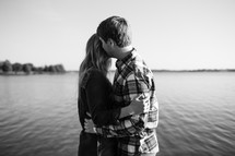 a couple embracing by a lake shore 