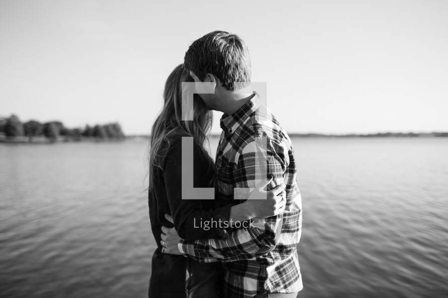a couple embracing by a lake shore 