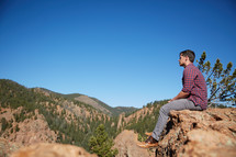 a man siting on a rock thinking 