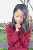 a girl praying outdoors 