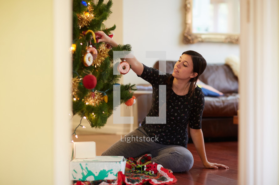 a mother putting gifts under a Christmas tree