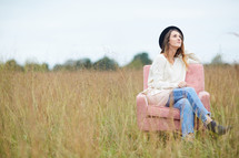 a woman sitting in a chair in a field looking up to God 