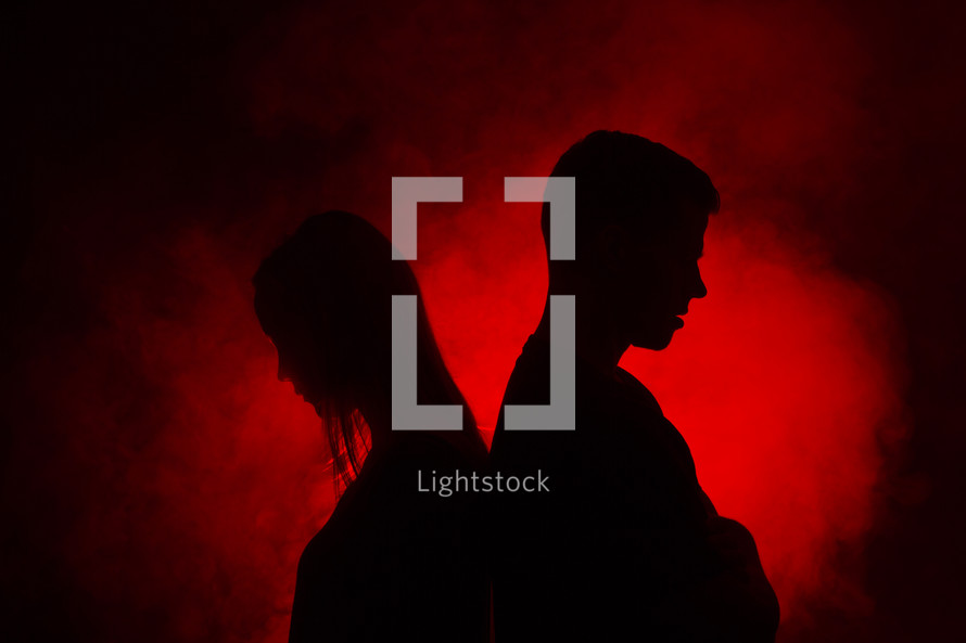 couple standing back to back in red glowing light 