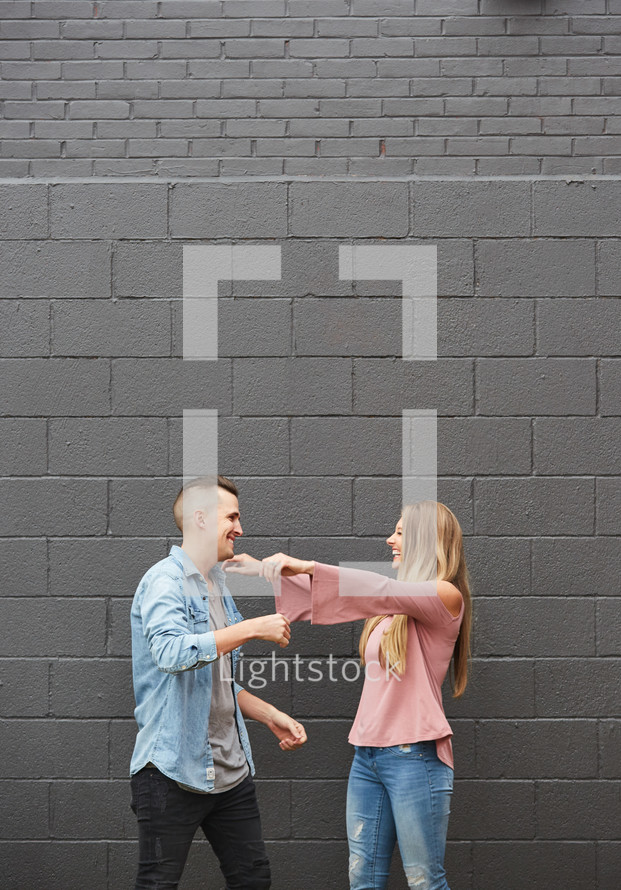a couple hugging in front of a gray wall 