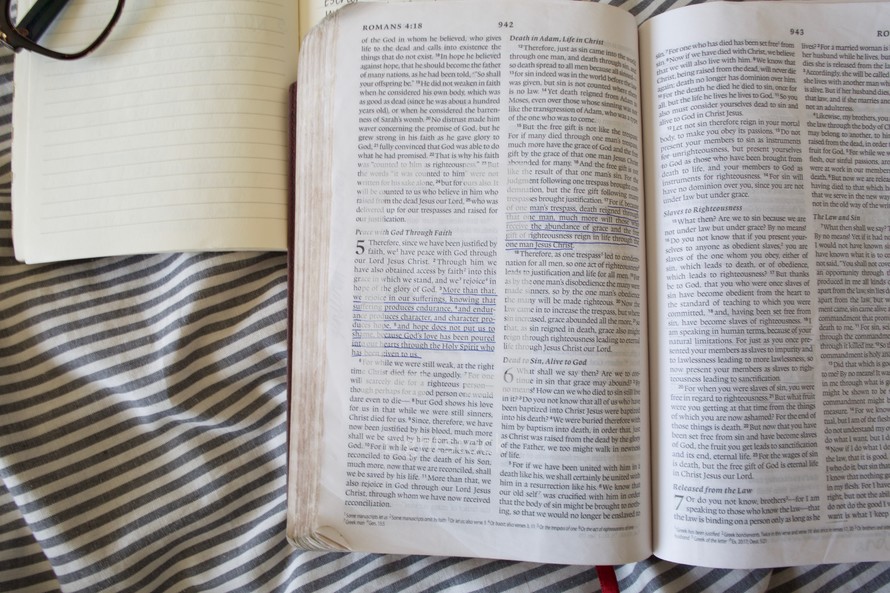 open Bible, reading glasses, and journal on a bed 