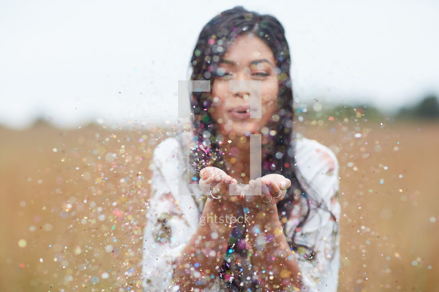young woman blowing confetti 