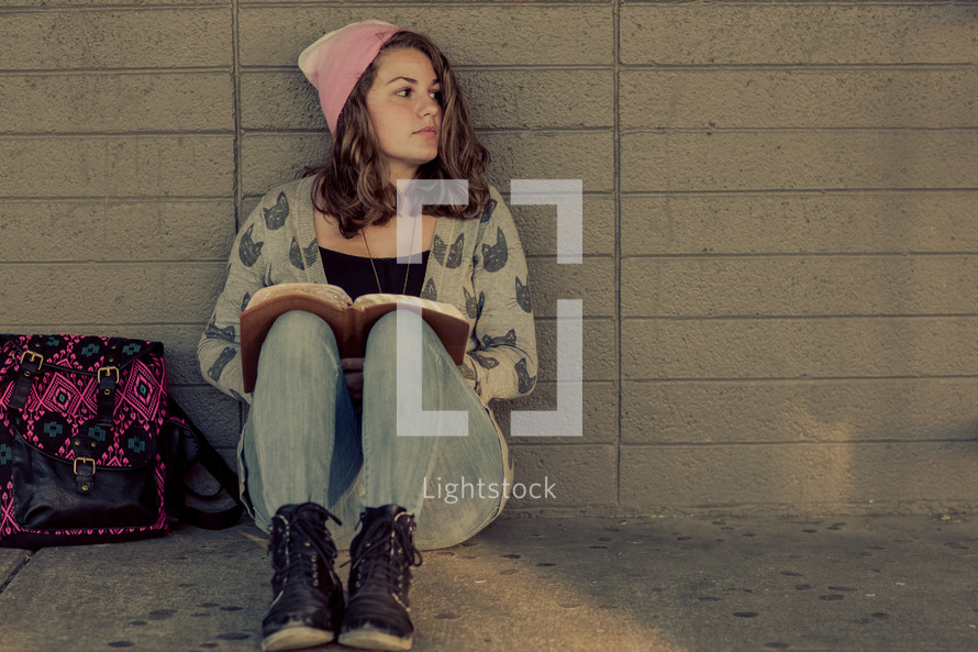 Teenage girl back to school studying, ready bible, campus, alone in a school hallway, wall, devotional