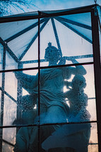 protected statues in a glass enclosure outdoors 