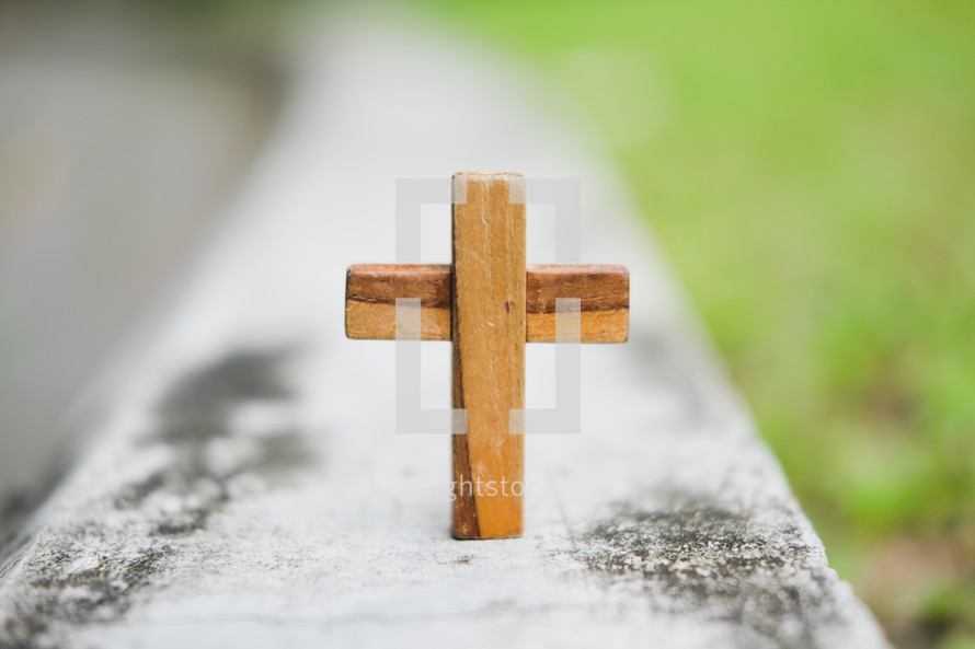 small wooden cross on a railing 
