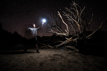 a man chasing a glowing light in a desert at night 