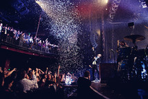 confetti falling on musicians on stage and an audience at a concert