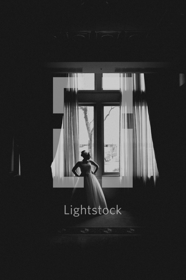 A bride poses in front of a window