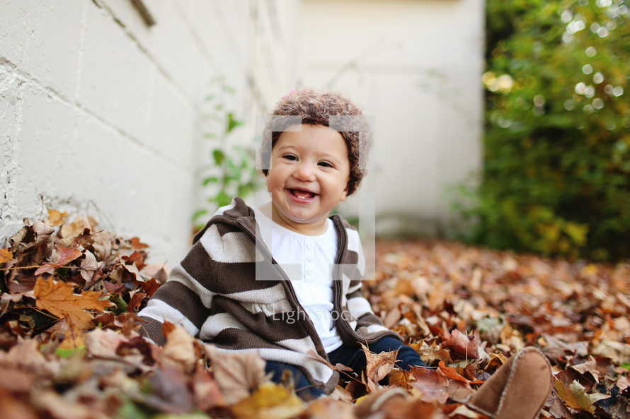Toddler playing in Autumn leaves