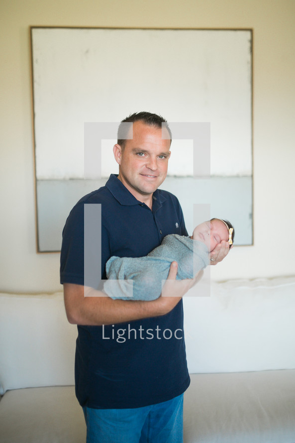 father holding a swaddled newborn baby 