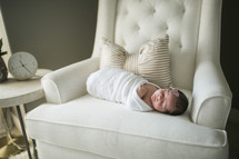 swaddled baby in a chair 