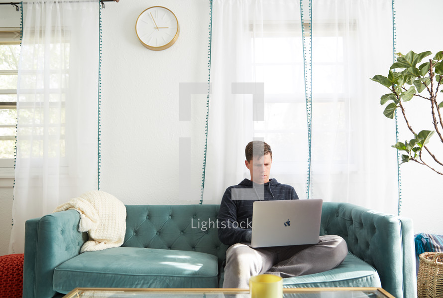 a man on a laptop sitting on a couch 