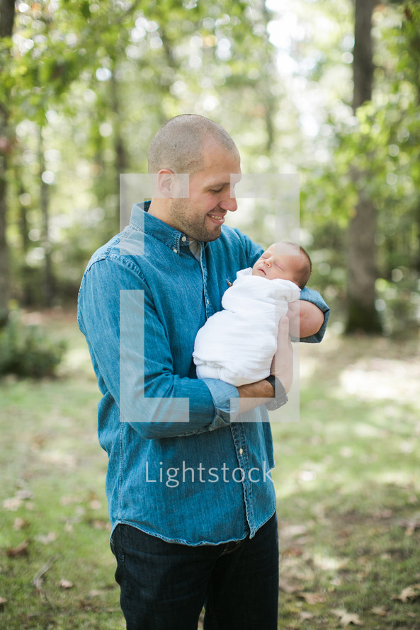 a father holding his newborn son outdoors 