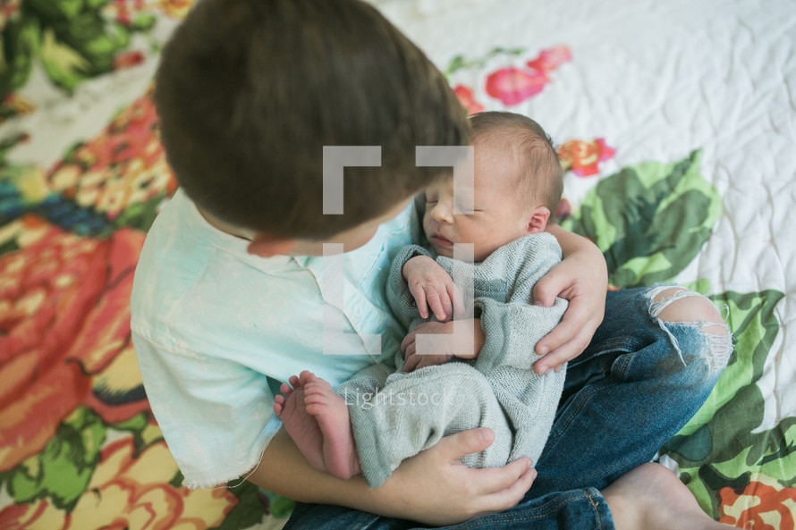 a big brother holding his newborn brother 