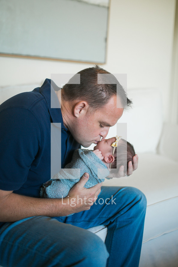  father holding a swaddled newborn baby 