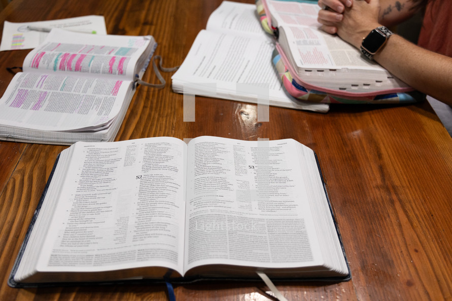Three open Bibles on wooden table in kitchen during women's Bible study and discipleship group